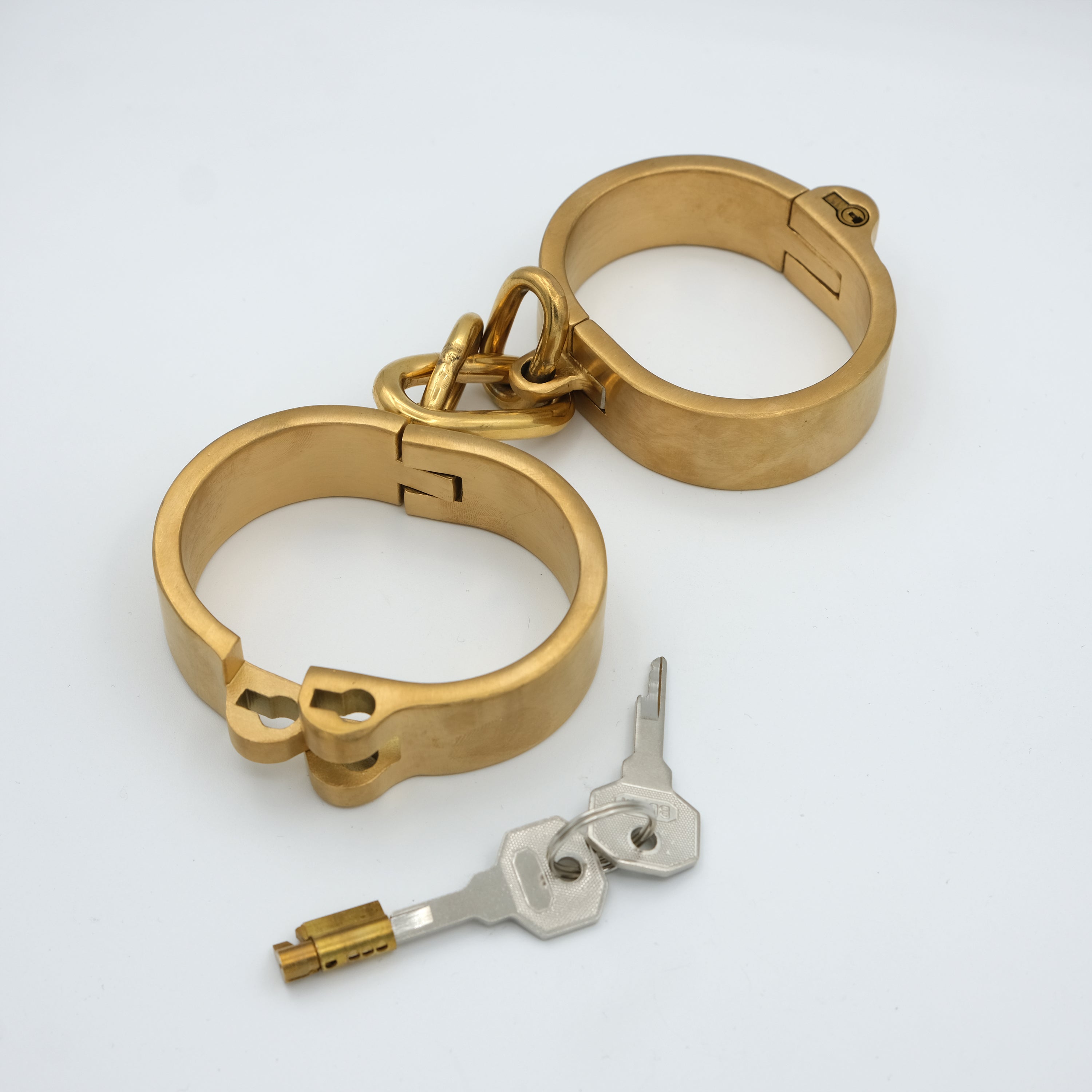 Gold flat handcuffs shown with the push-in lock cylinder and two keys