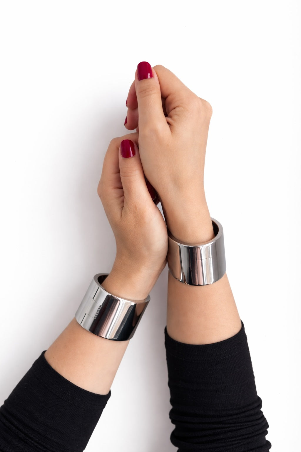 Pair of polished steel deSade wrist bands worn on a model's wrists