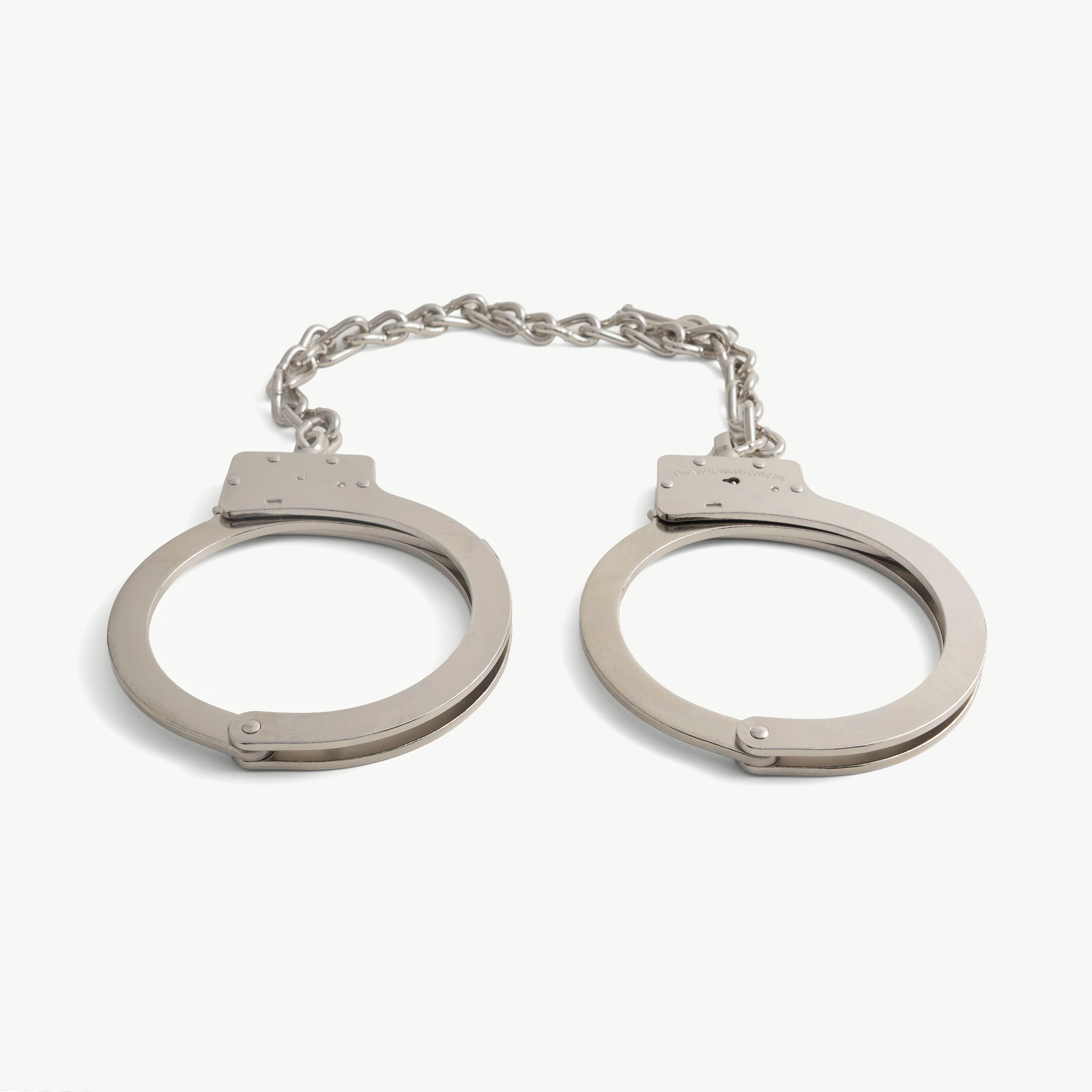 Pair of closed oversized steel ankle cuffs joined by a short heavy chain