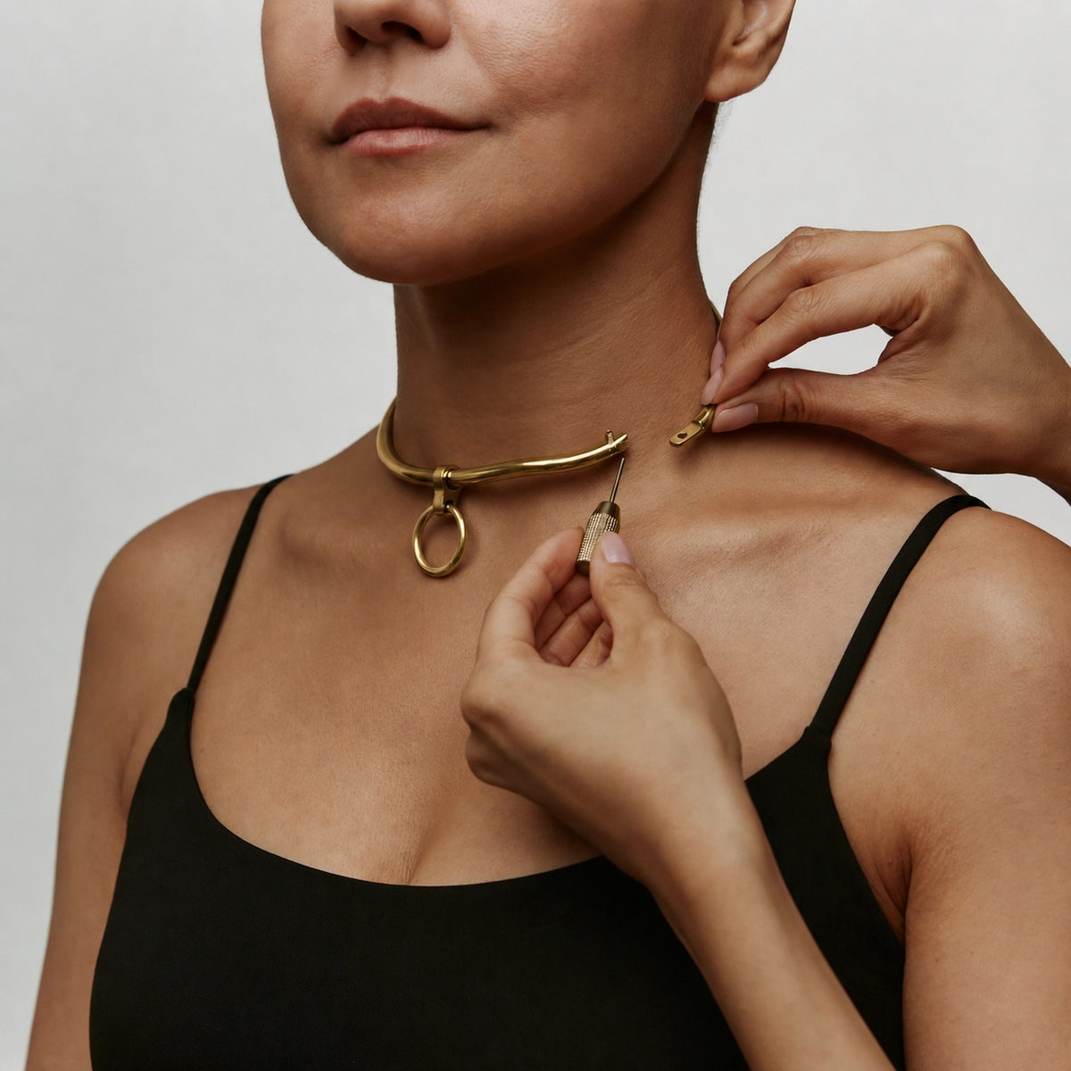 deSade gold day collar being closed on the neck, close-up of the hex lock
