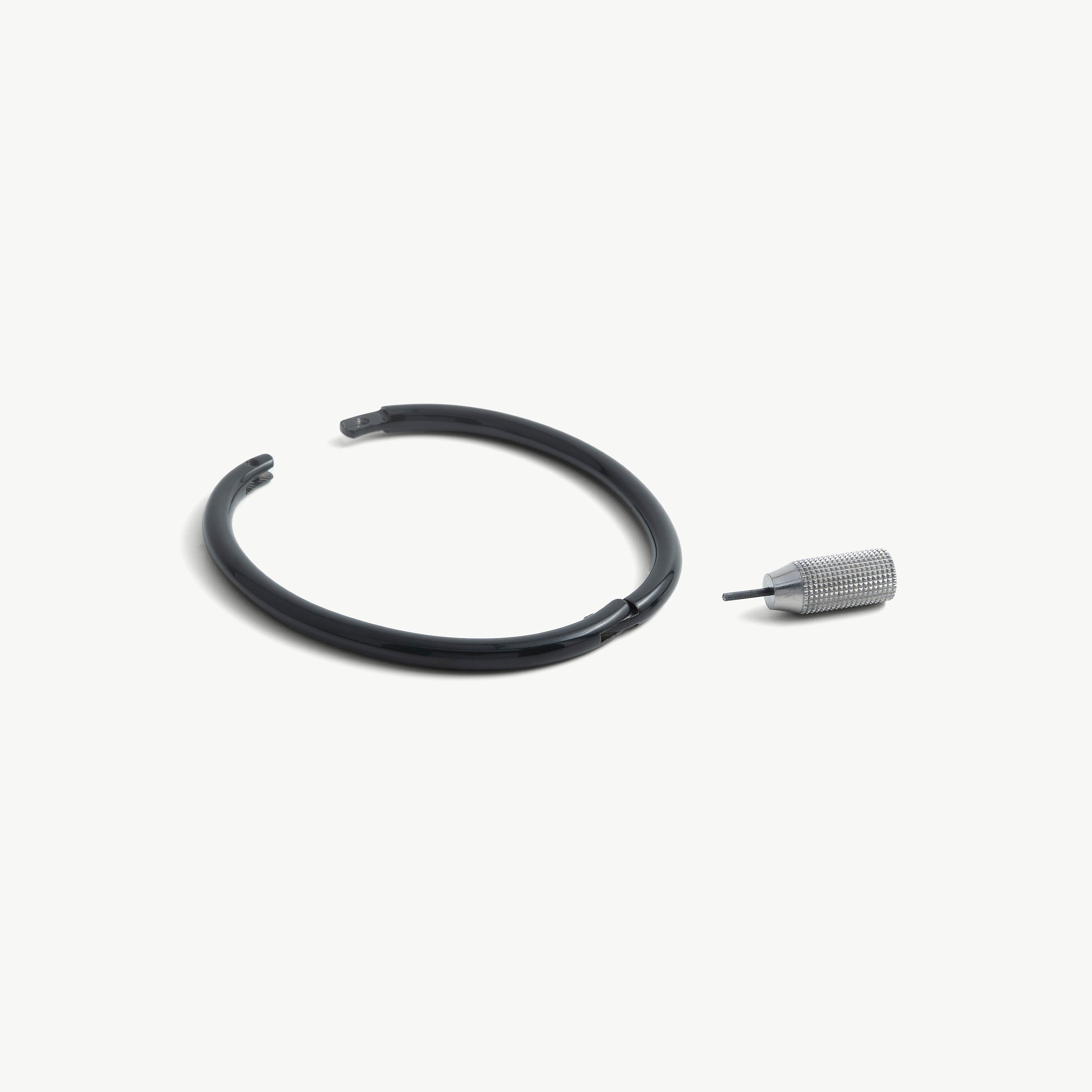 deSade black ankle bracelet shown open beside its hex key tool