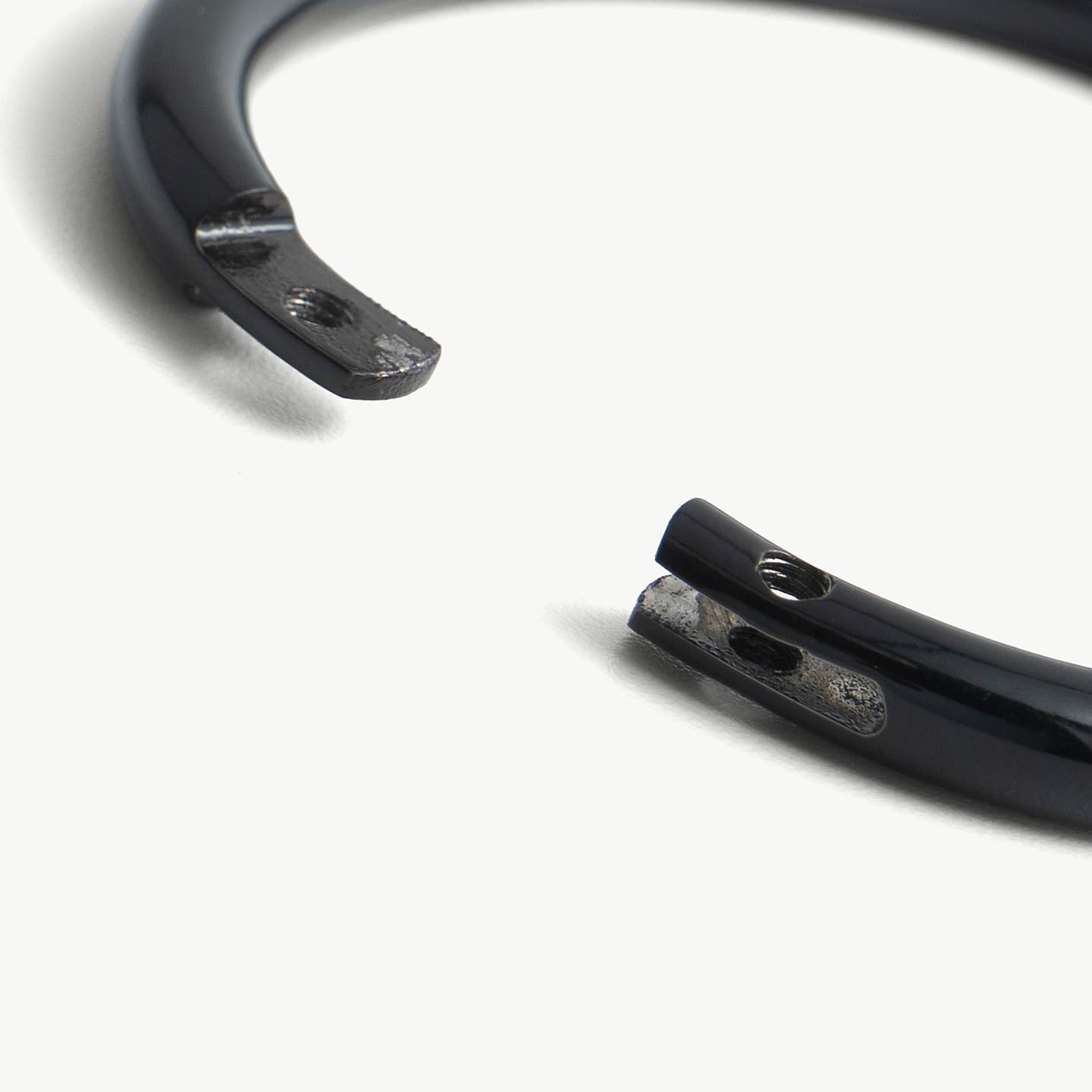 Extreme close-up of the deSade black wrist bracelet's open ends and lock screw hole