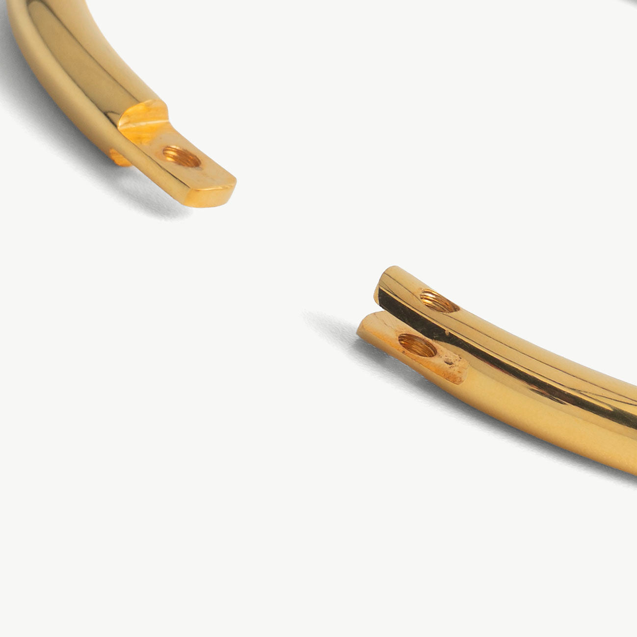 Extreme close-up of the deSade gold bracelet's open ends and hex lock screw hole