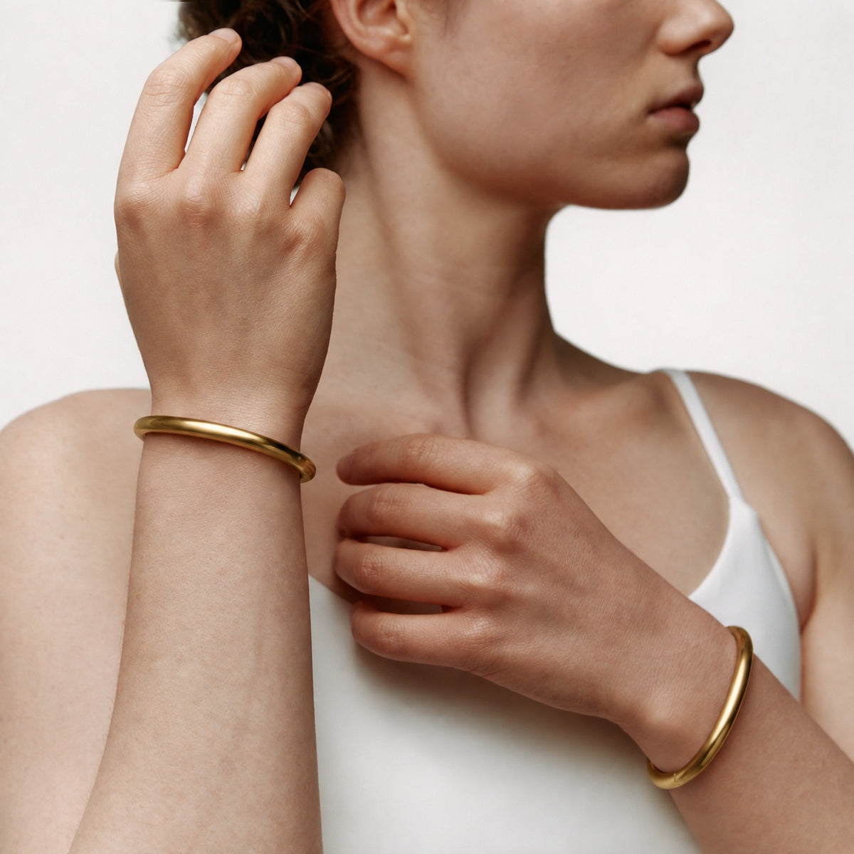 Gold deSade 6mm wrist bracelets worn singly on both wrists, hands free