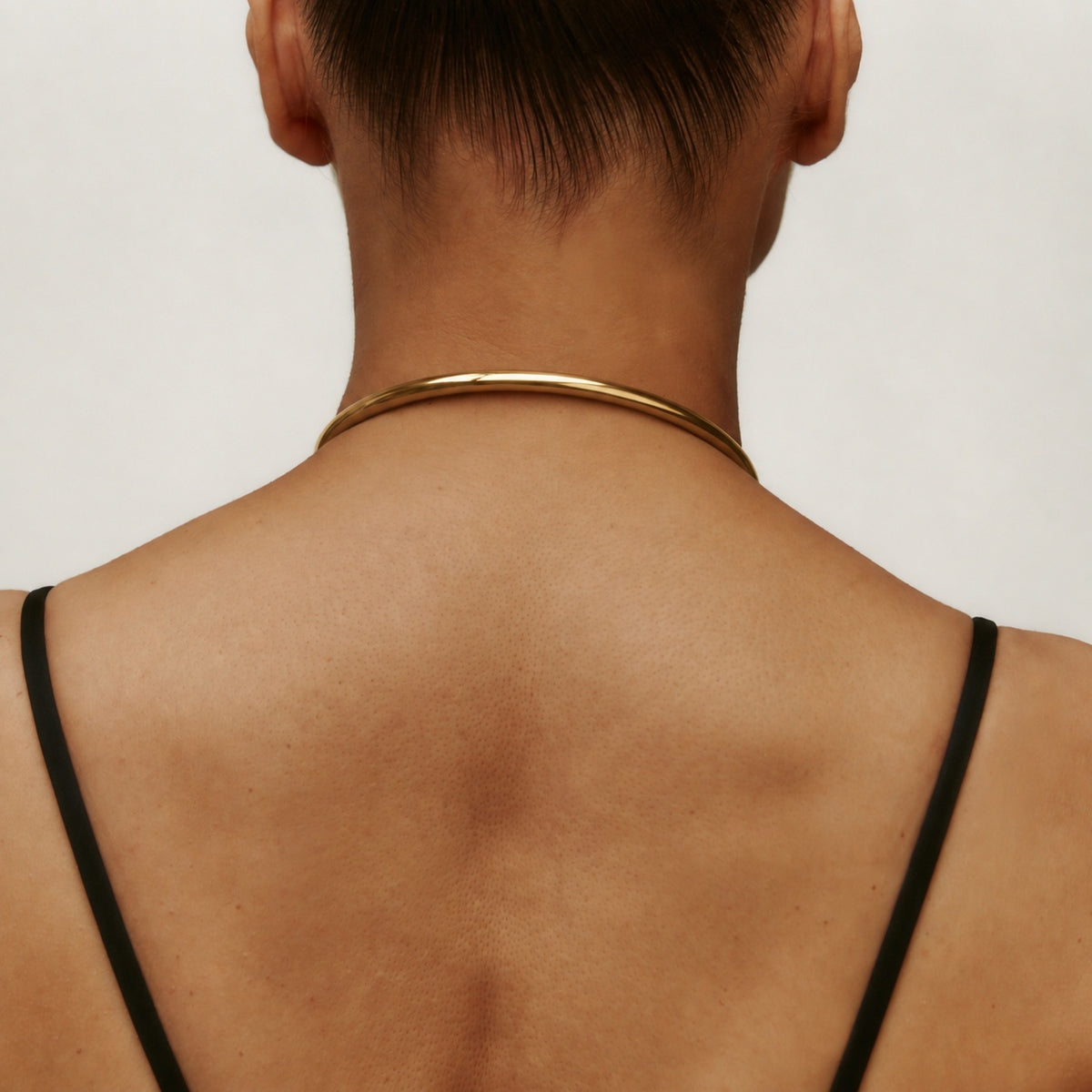 Back view of the gold deSade round day collar worn on the neck