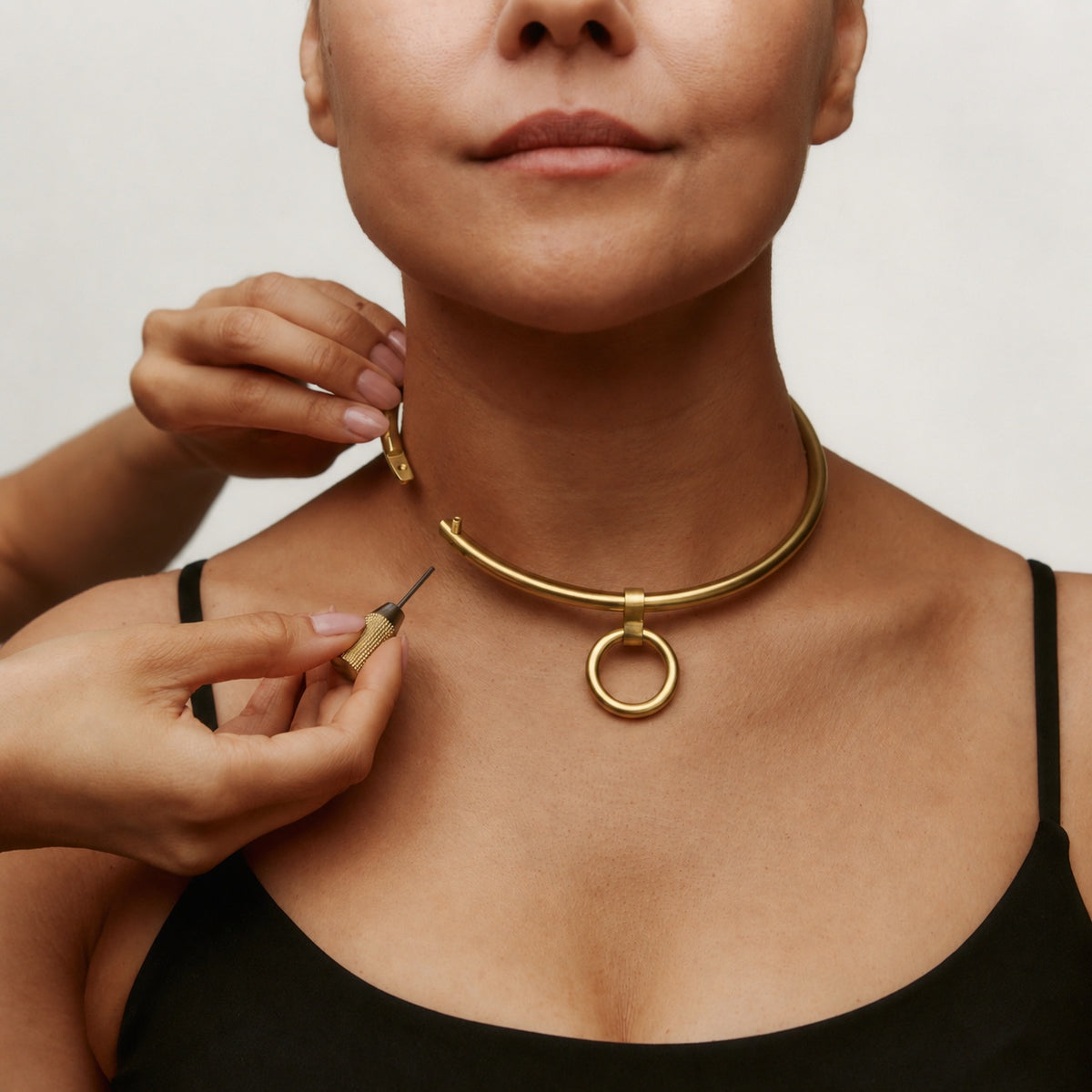 Gold deSade round day collar being locked on the neck with the hex key