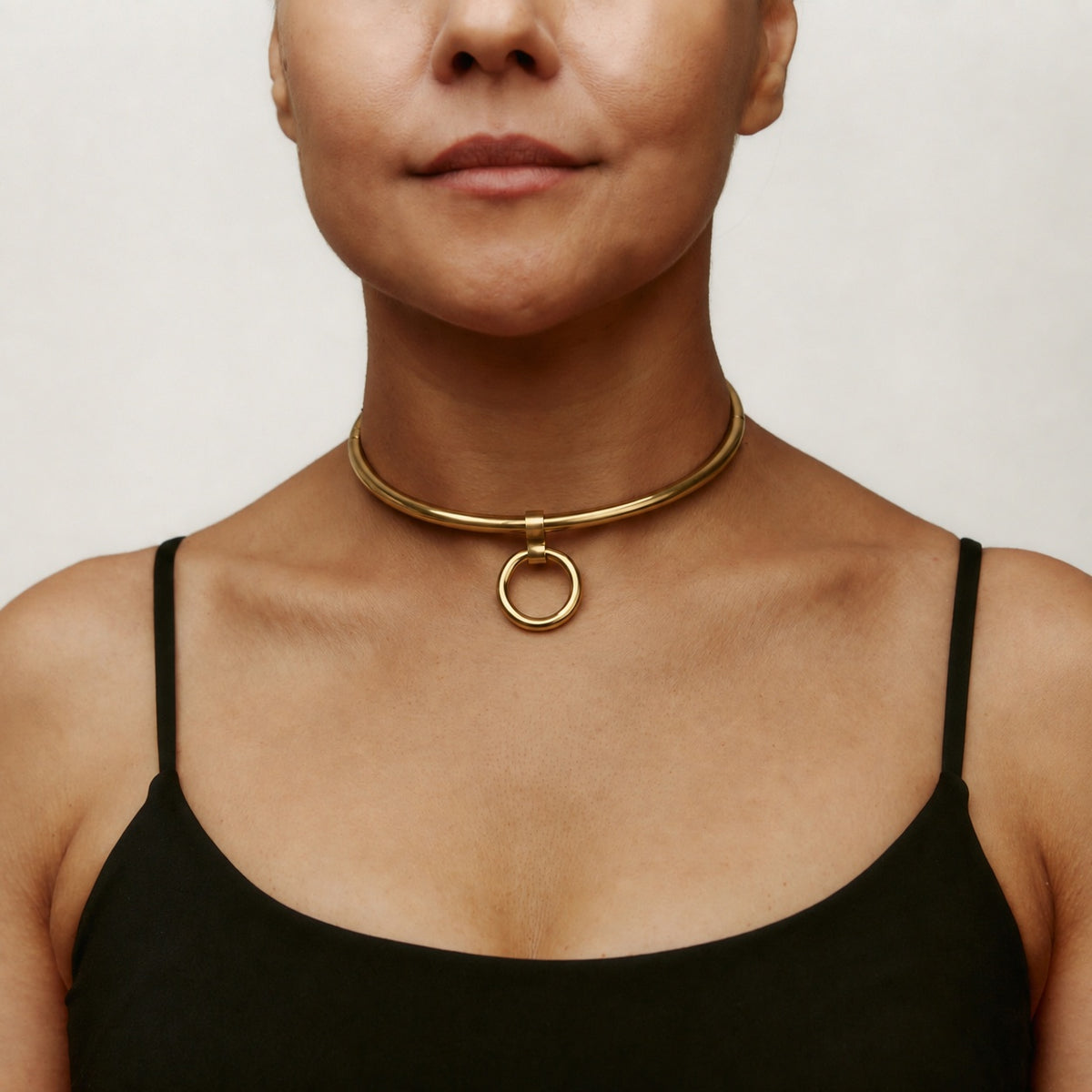 Gold deSade round day collar worn on the neck, front view with the O-ring