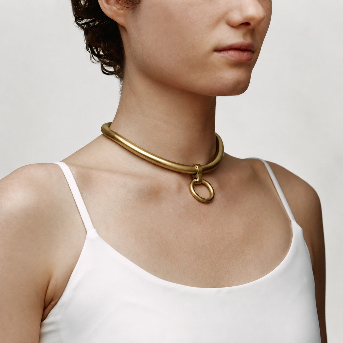 deSade gold ergonomic day collar with front O-ring worn on the neck, angled view