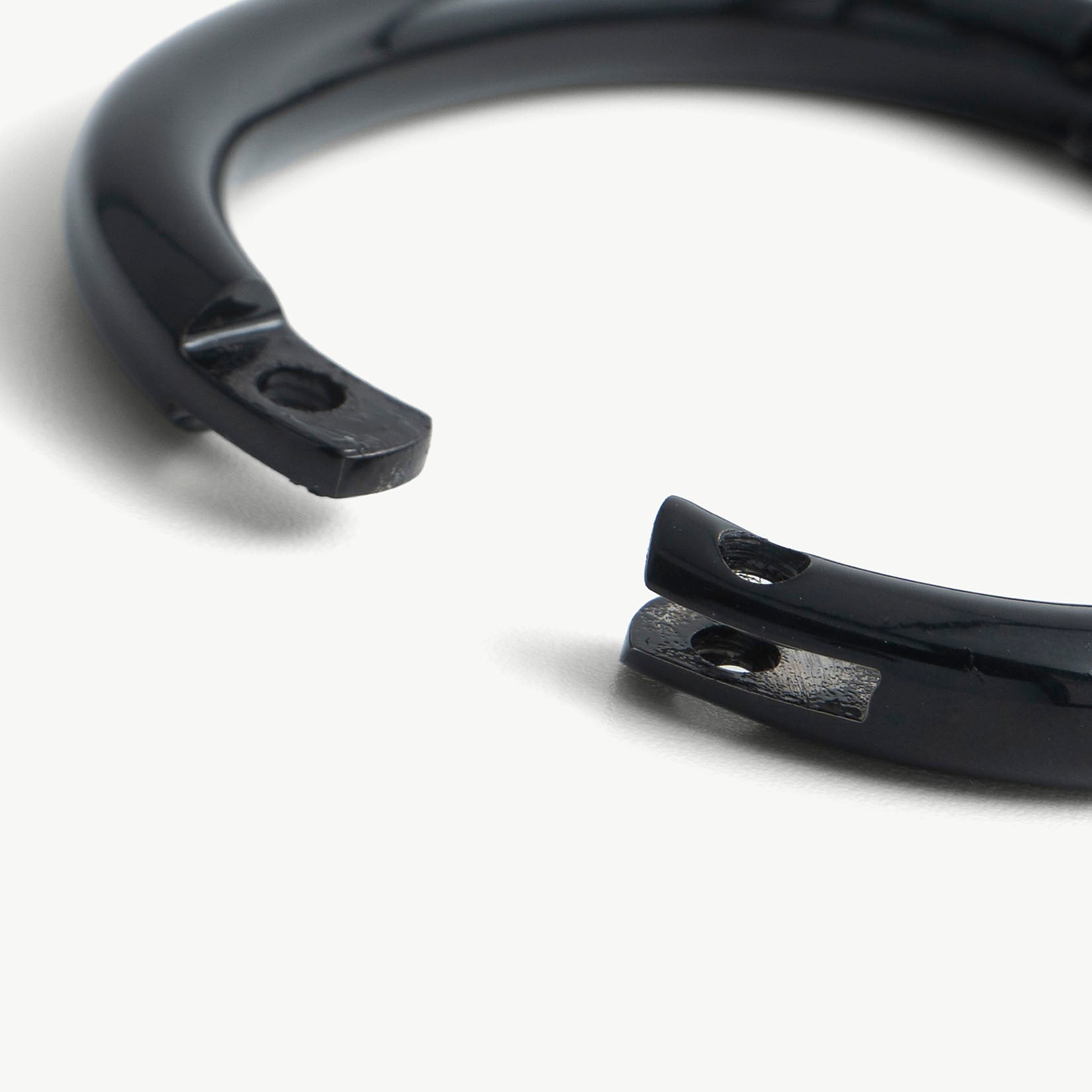 Extreme close-up of the deSade black wrist bracelet's open ends and lock screw hole