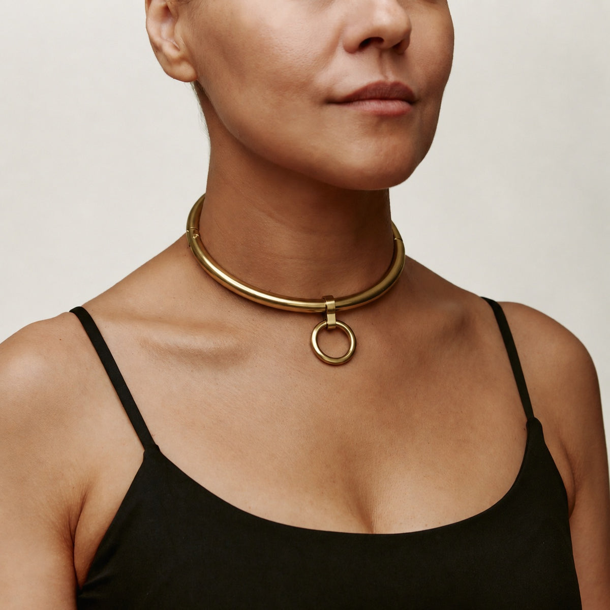Gold deSade 8mm round day collar with O-ring worn on the neck, angled view