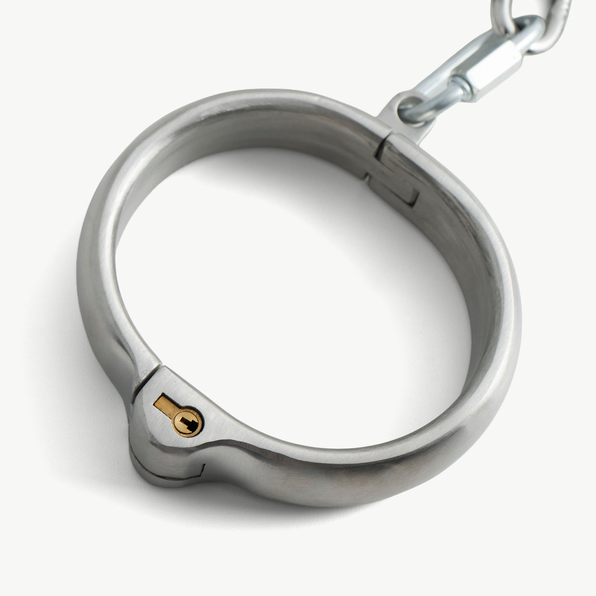 Close-up of a rounded legcuff with its brass push-in lock and chain link