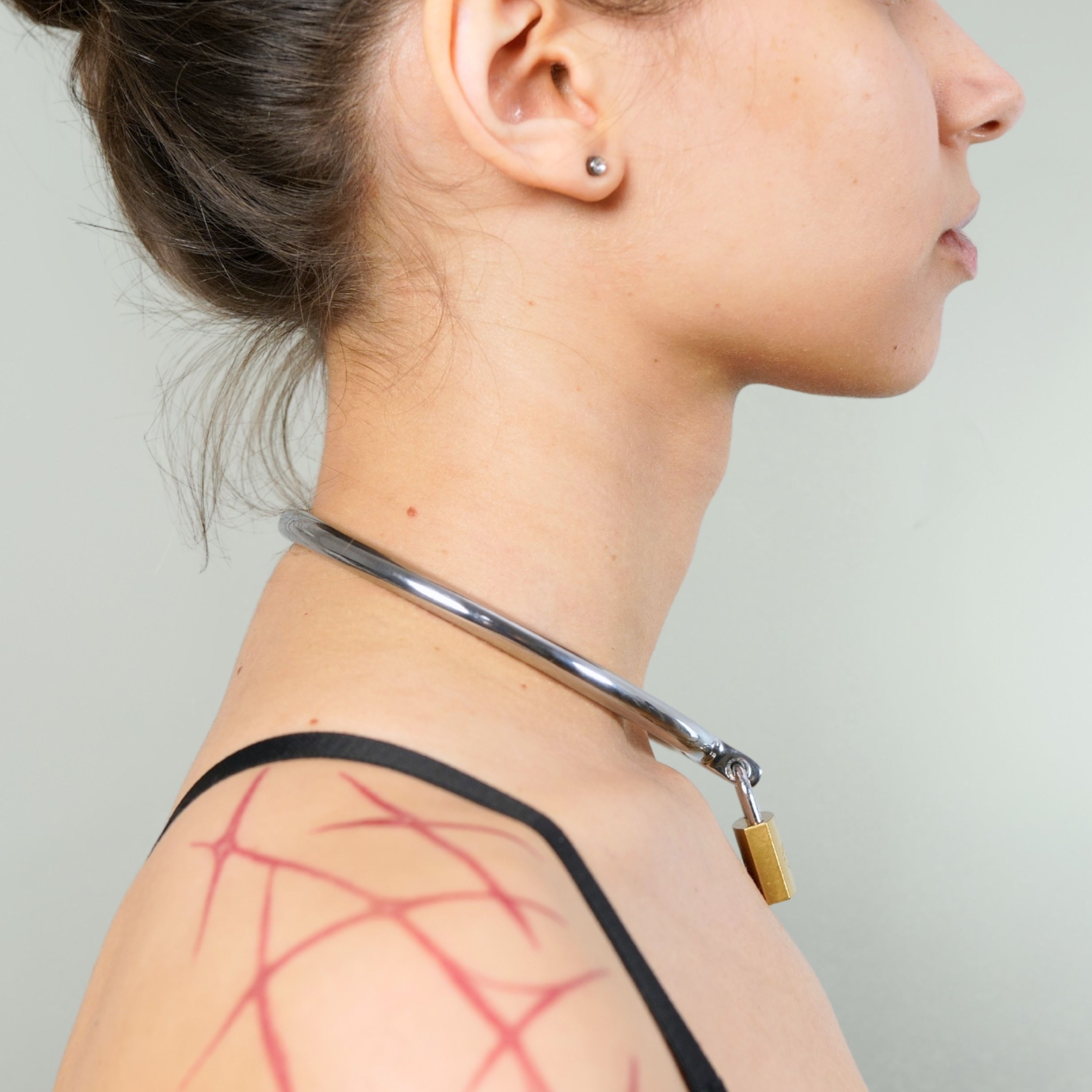Steel day collar with padlock worn on a model's neck, alternate view