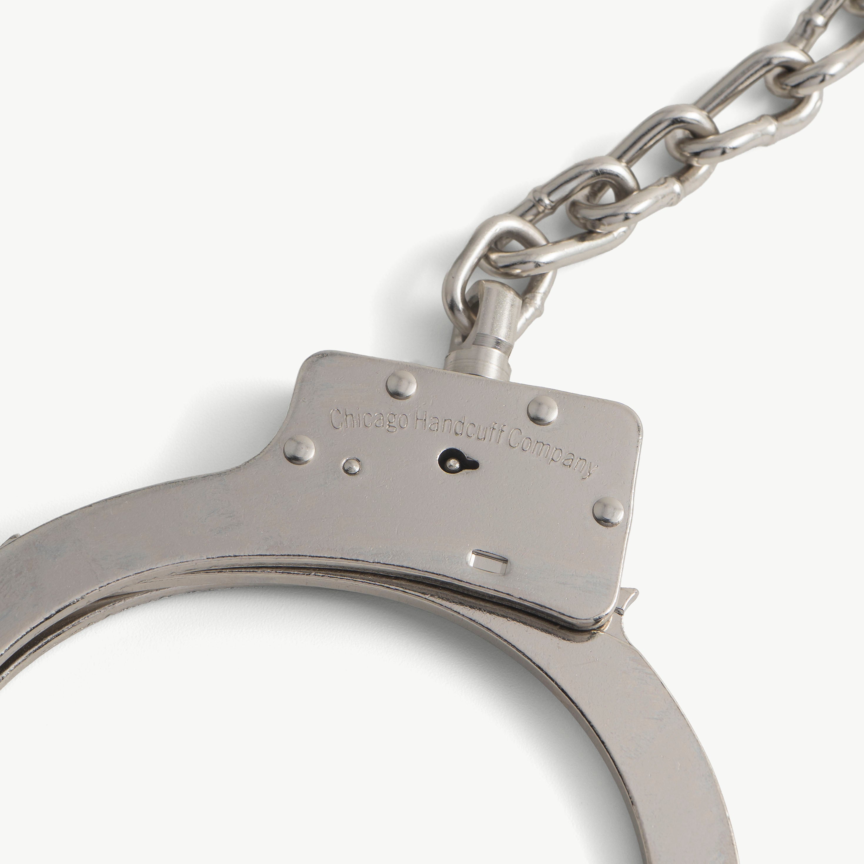 Close-up of steel leg iron lock bar engraved Chicago Handcuff Company with attached chain