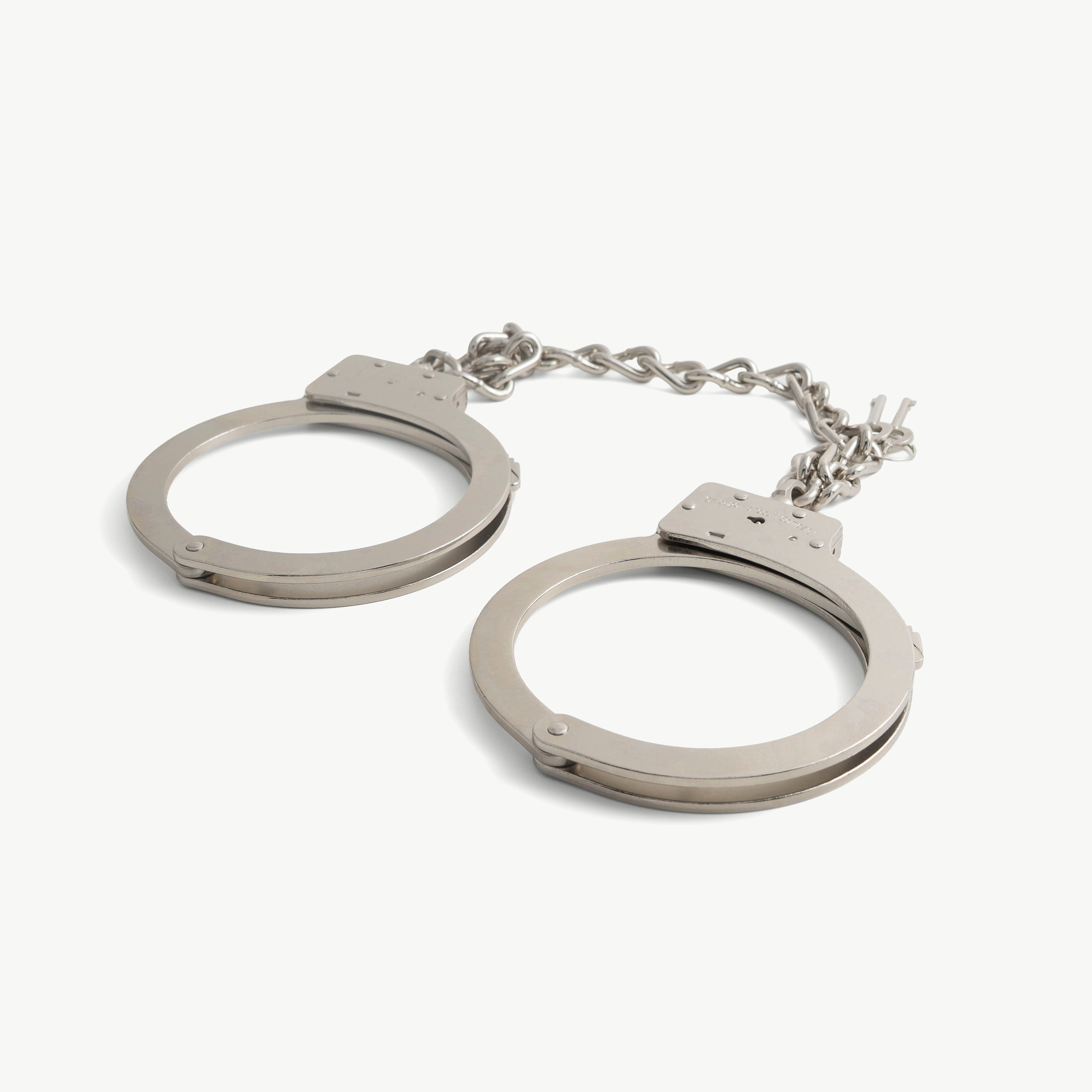 Oversized steel boot cuffs opened flat, both ankle rings unlocked with chain and keys