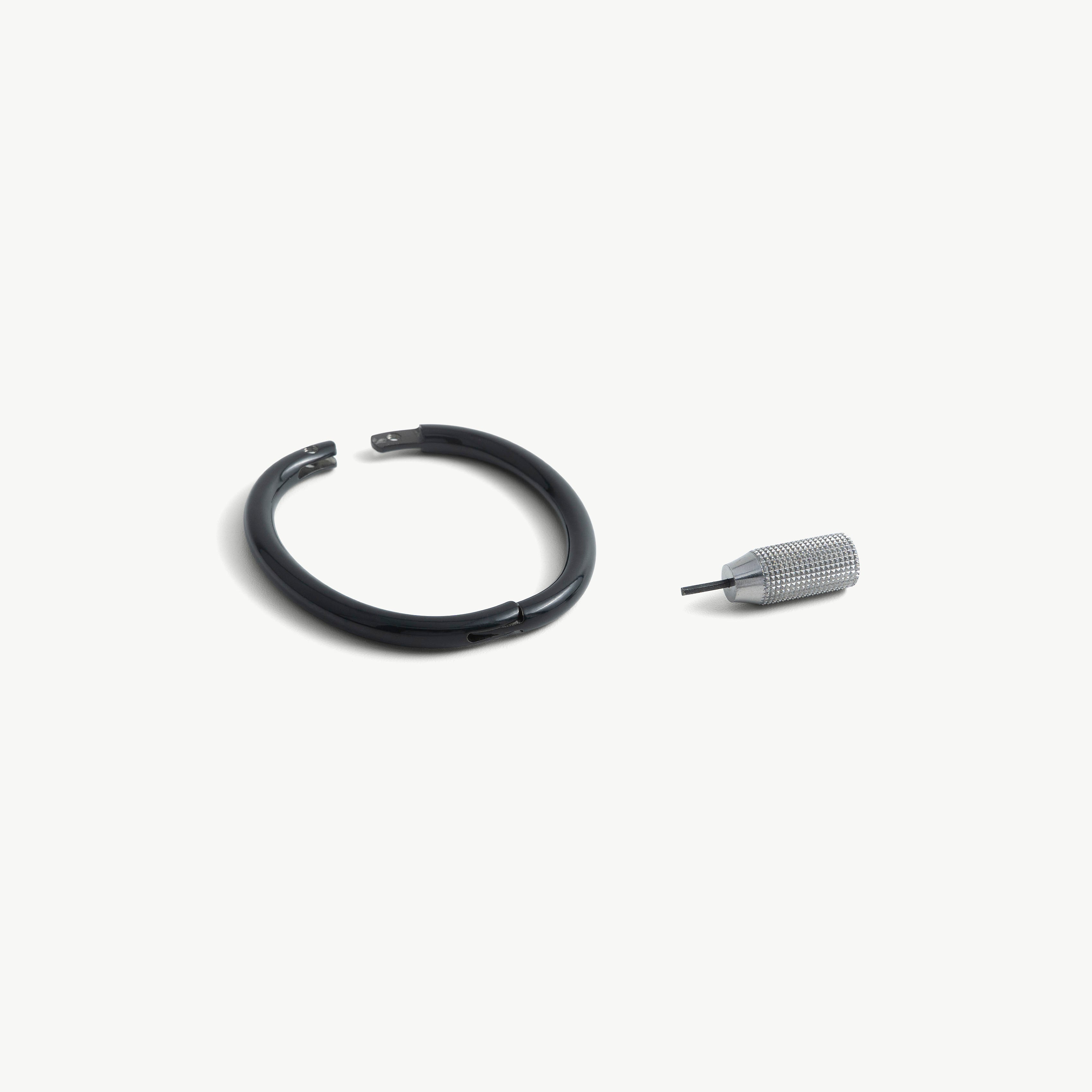 deSade black wrist bracelet shown open beside its hex key tool