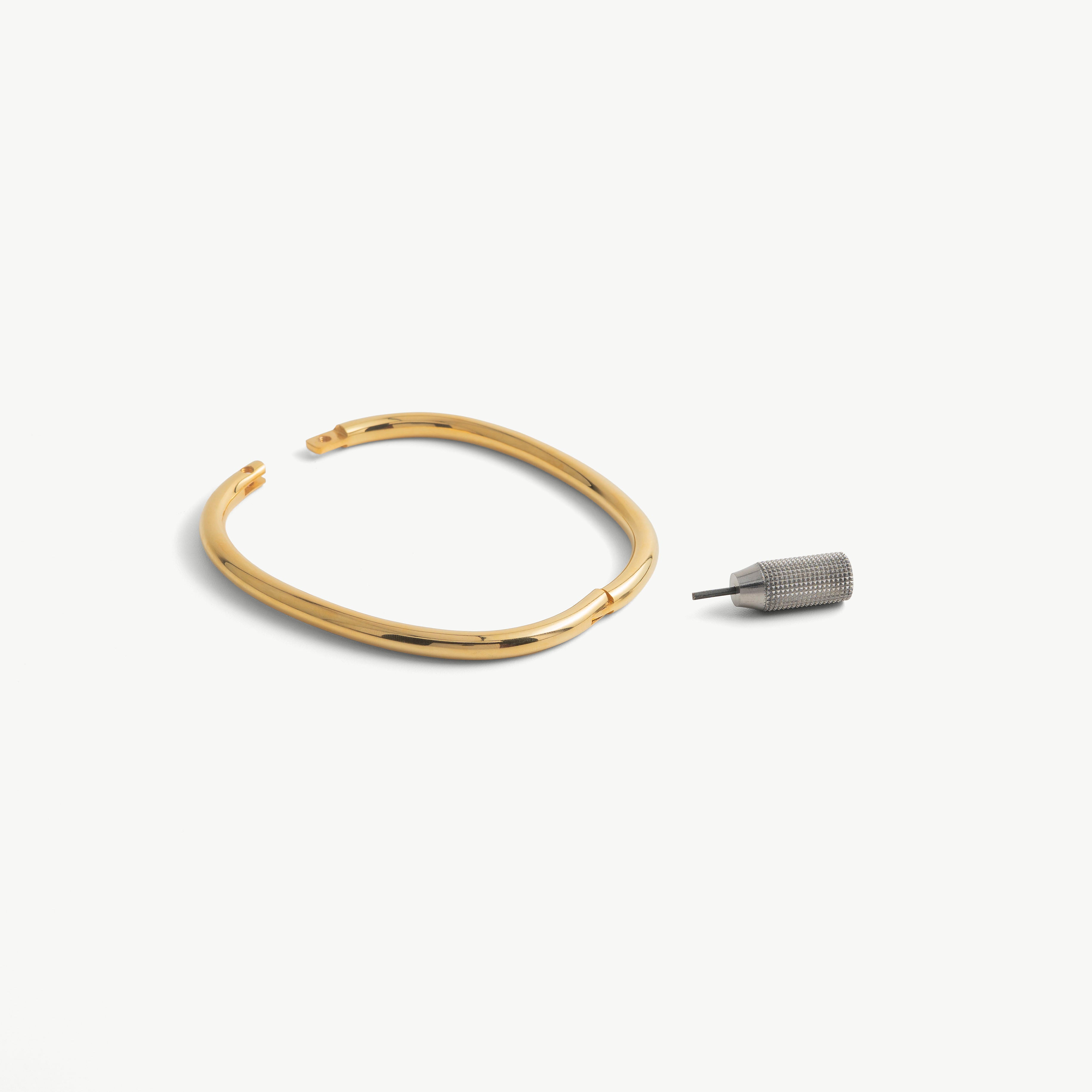 deSade gold ankle bracelet shown open beside its hex key tool