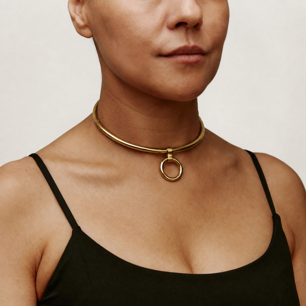 Gold deSade 6mm round day collar with O-ring worn on the neck, angled view