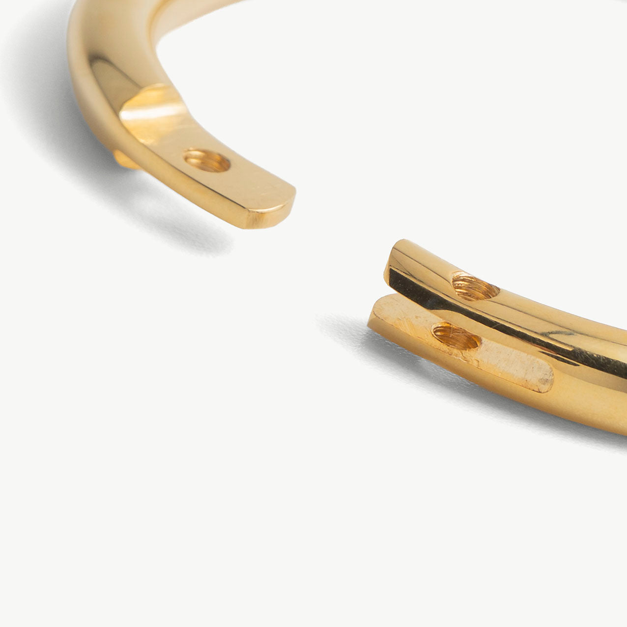 Extreme close-up of the deSade gold wrist bracelet's open ends and lock screw hole