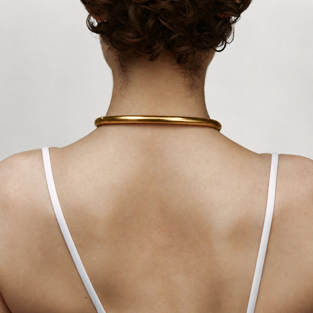 Back view of the deSade gold ergonomic day collar worn on the neck