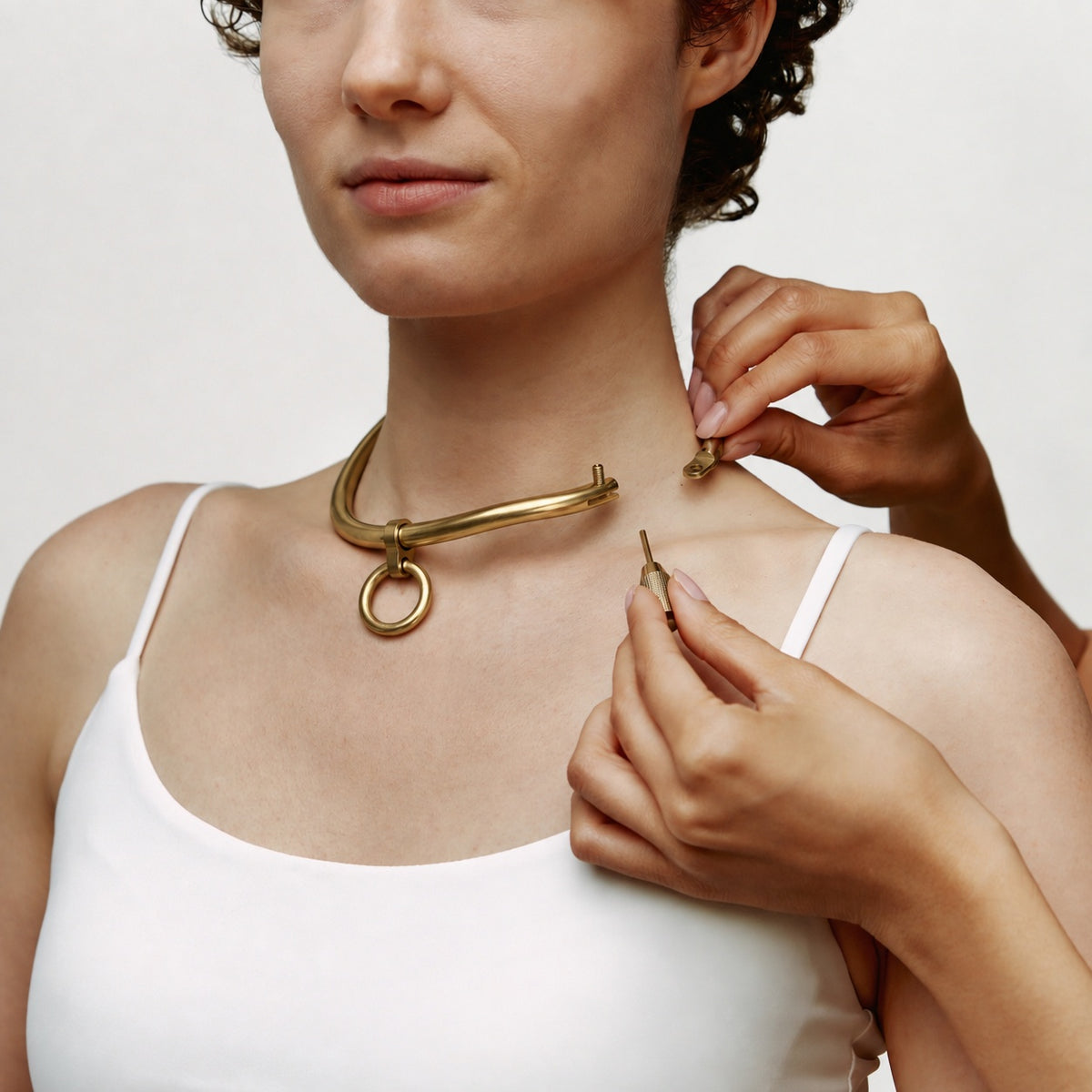 deSade gold day collar being opened at the hex lock while worn, showing the hex key
