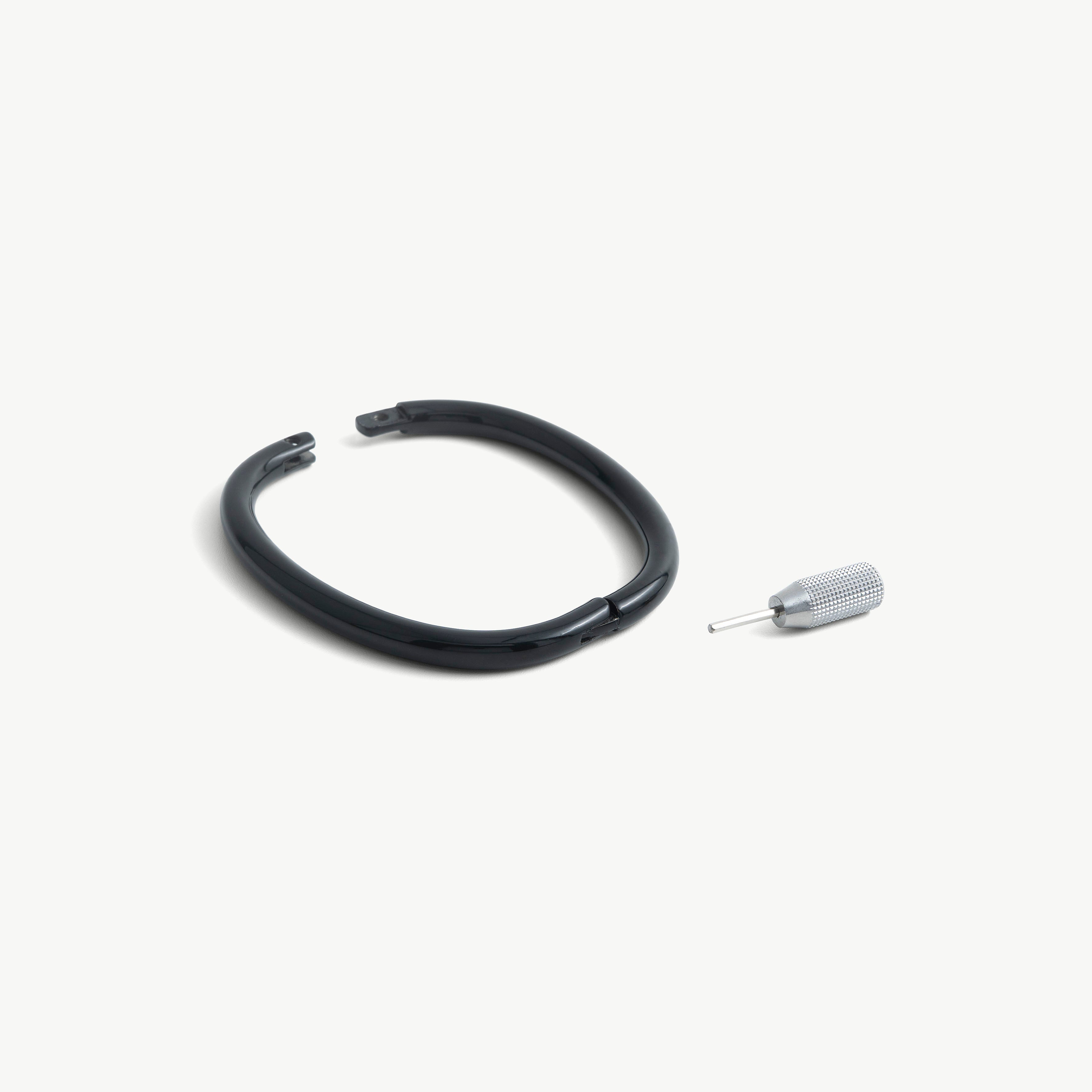 deSade black ankle bracelet shown open beside its hex key tool