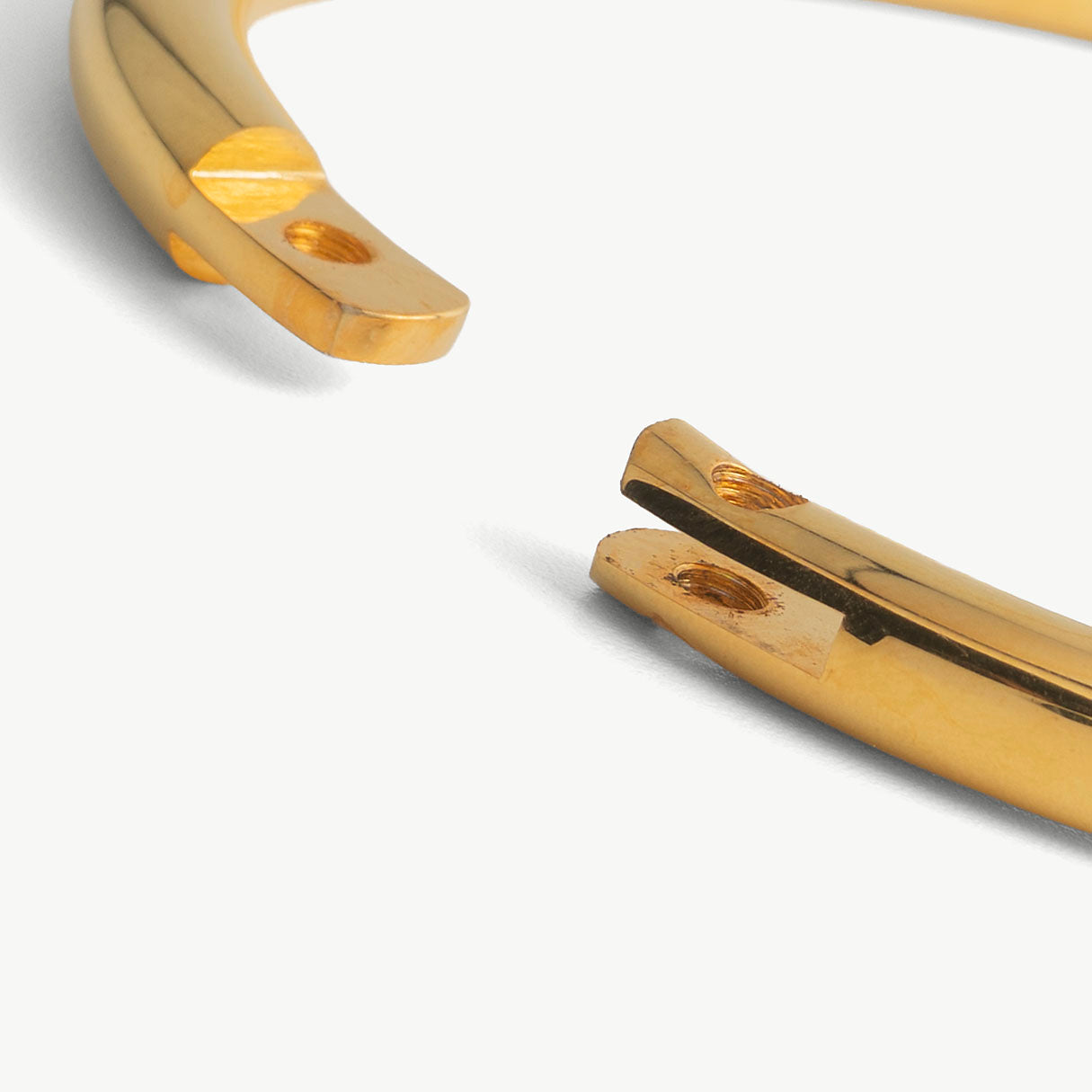 Extreme close-up of the deSade gold bracelet's open ends and hex lock screw hole