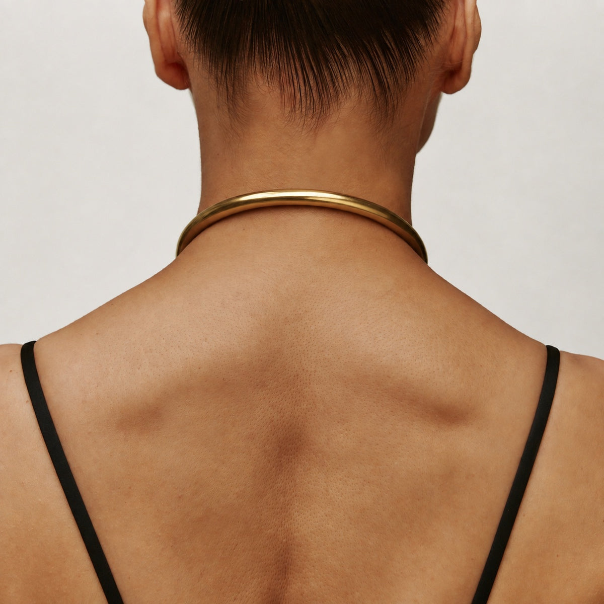 Back view of the gold deSade 8mm round day collar worn on the neck