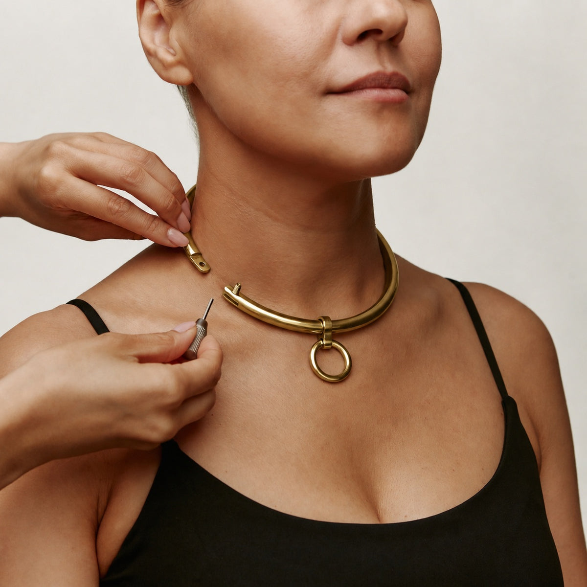 Gold deSade 8mm round day collar being locked on the neck with the hex key