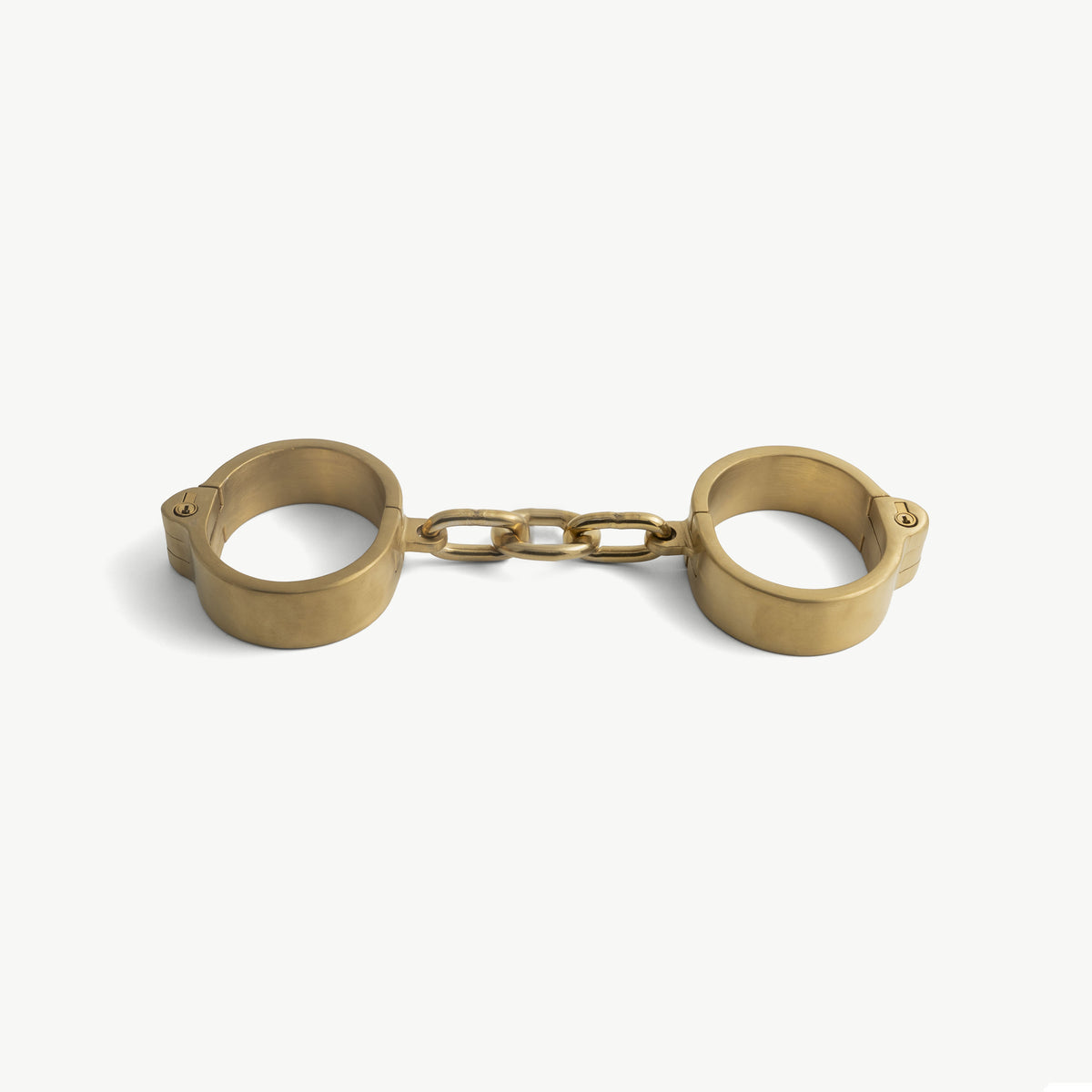 Age of Bondage gold flat handcuffs, two rigid stainless steel cuffs linked by a fixed three-link chain
