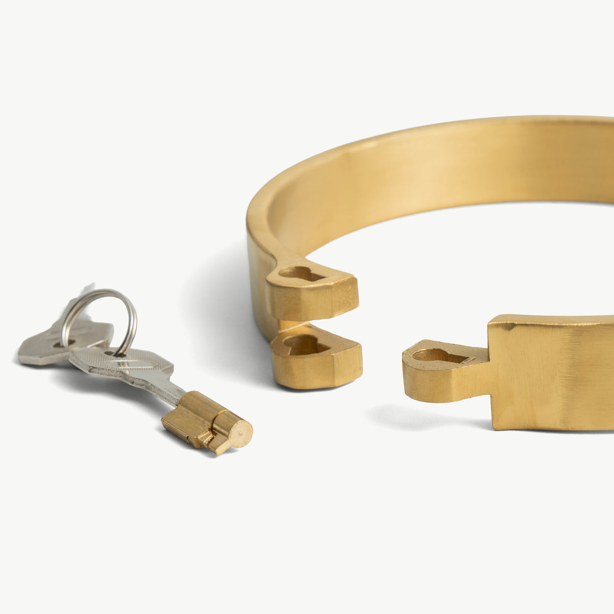 Close-up of the gold flat collar's open lock ends beside the push-in lock and key