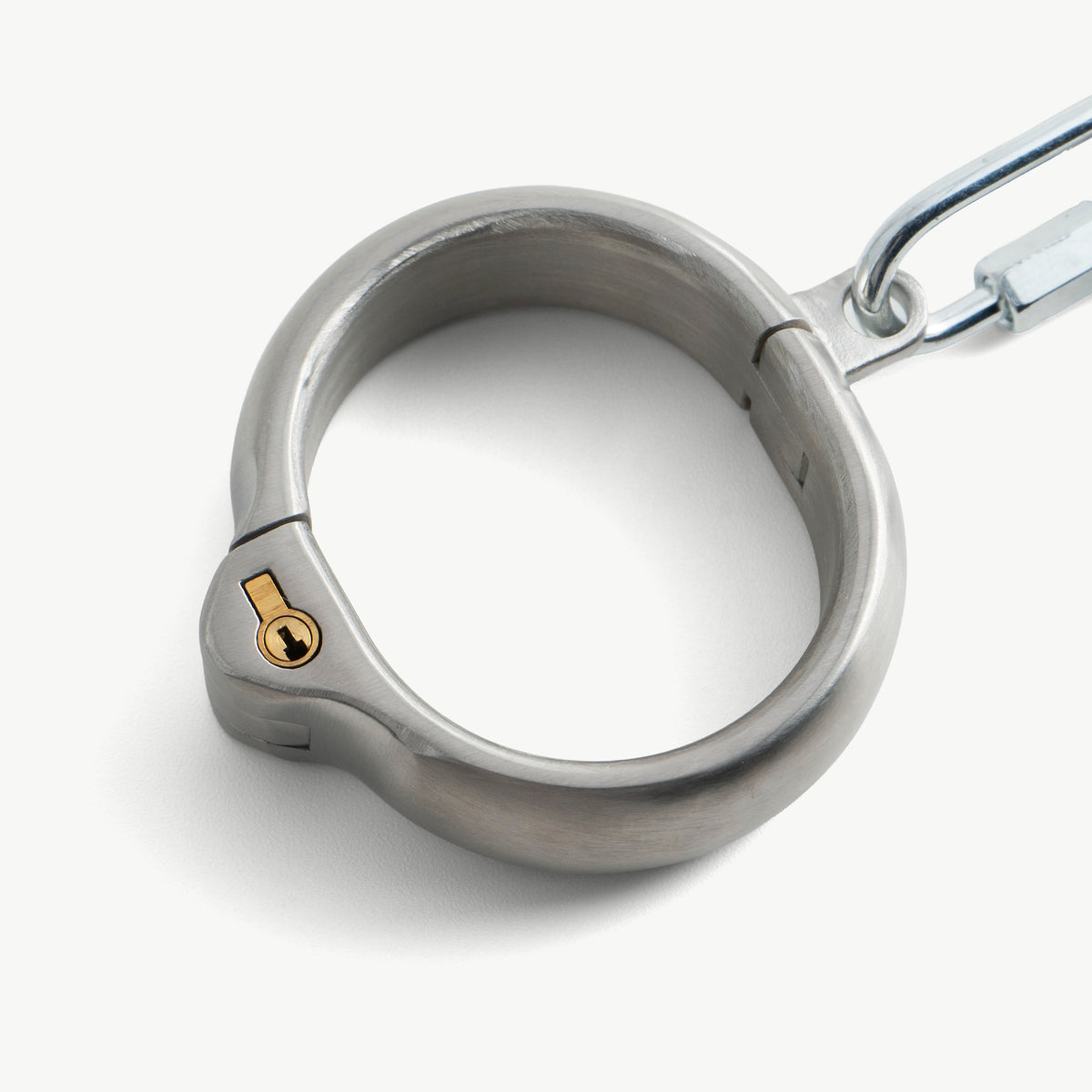 Close-up of a rounded handcuff with its brass push-in lock and connecting link