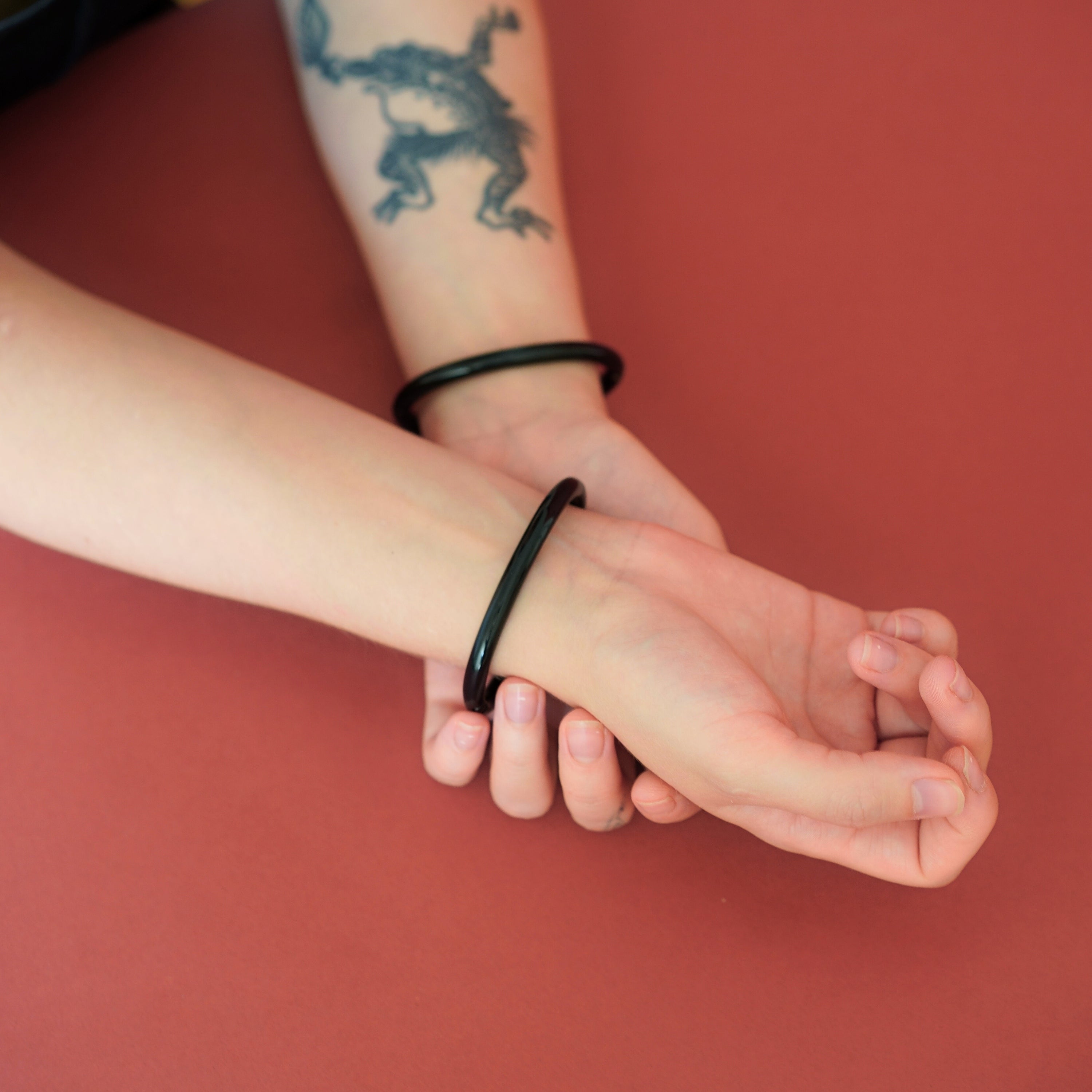 Pair of deSade black wrist bracelets worn on a model's wrists