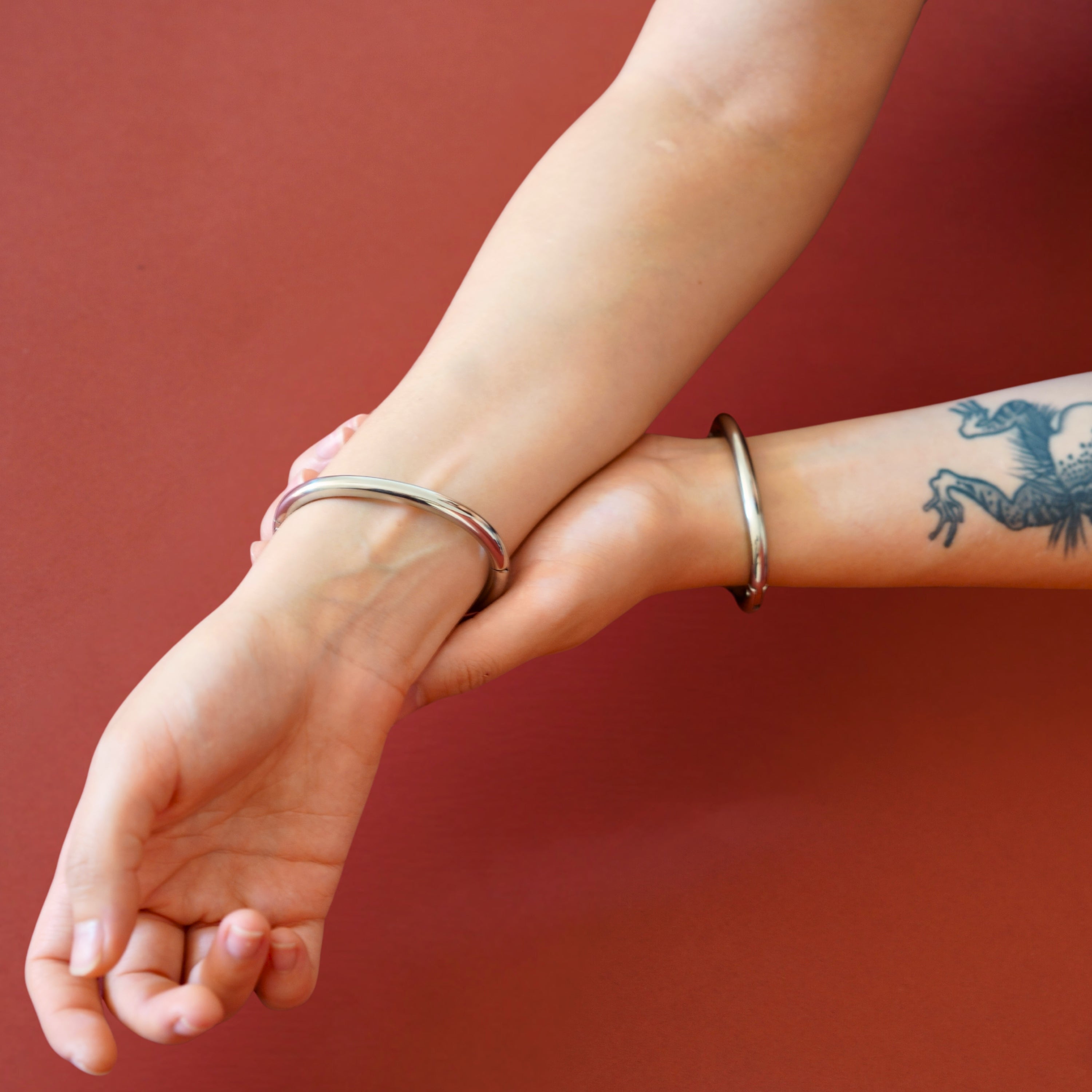 Pair of deSade silver wrist bracelets worn on a model's wrists