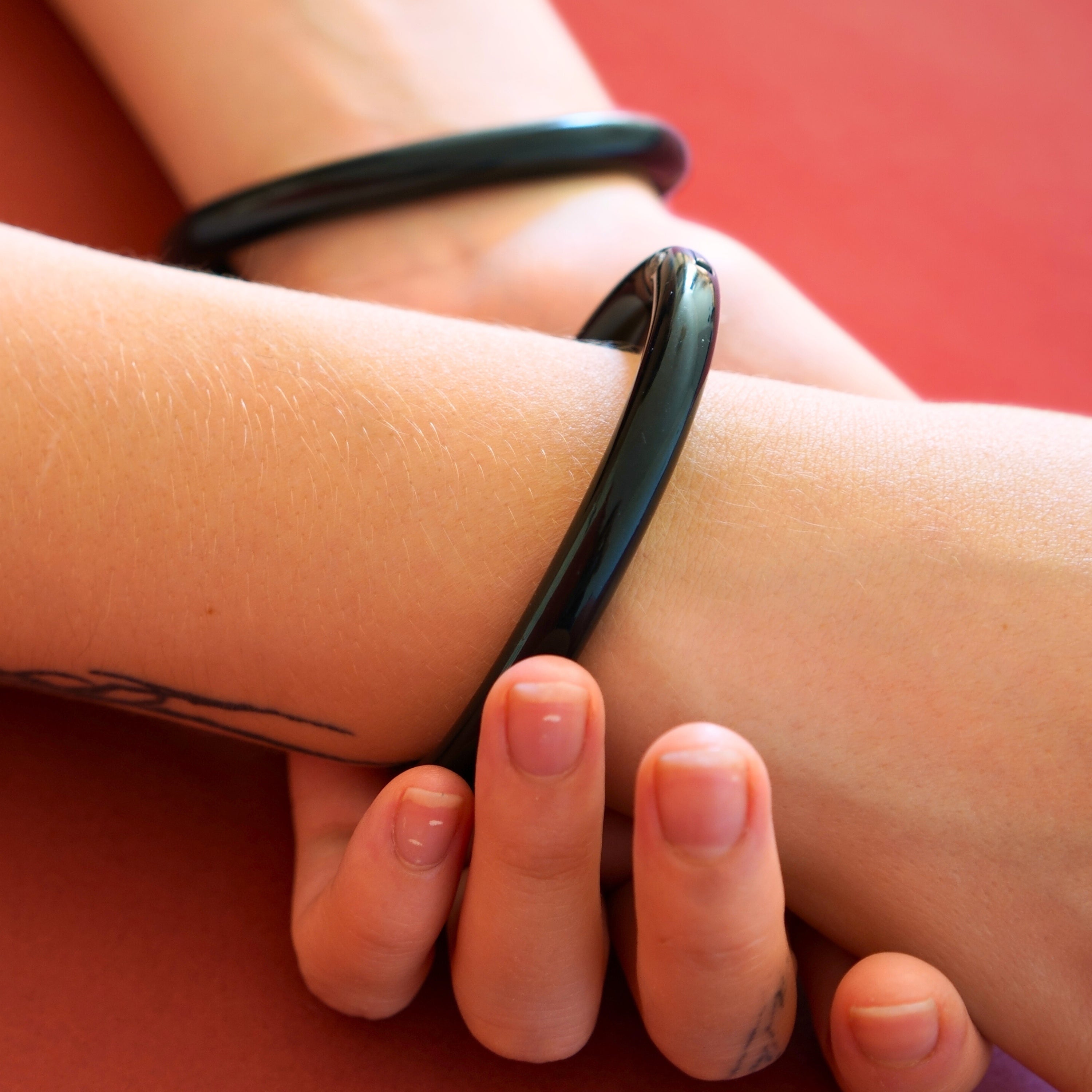 Pair of deSade black wrist bracelets worn on a model's wrists